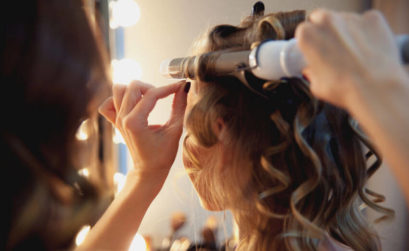 hairdresser curling hair with electric curling tong for party season