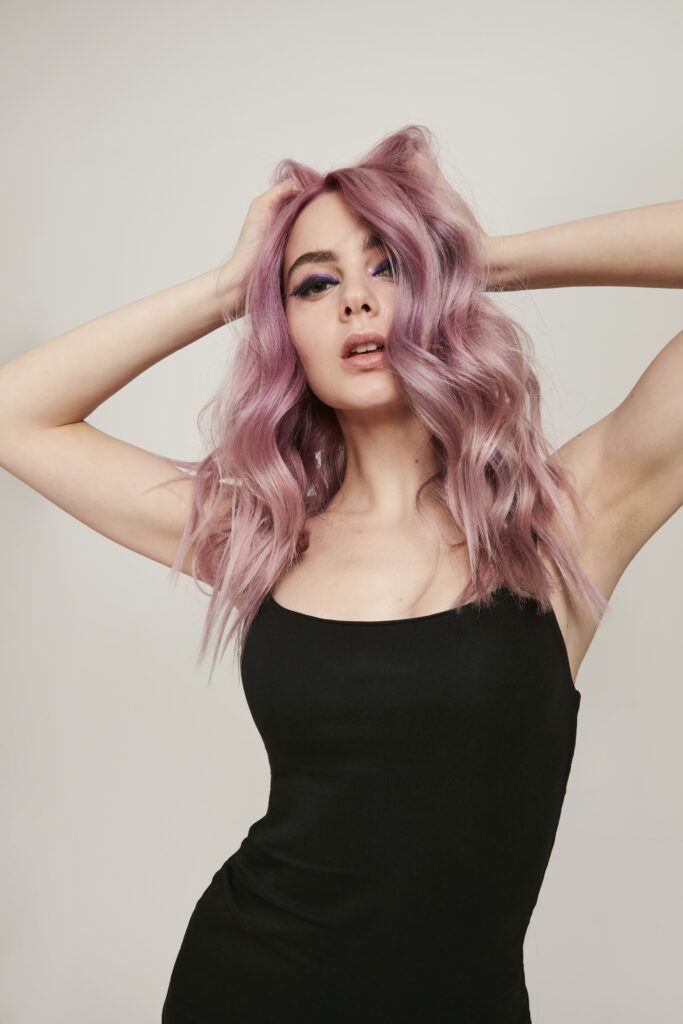 woman with lilac long hair with her hands on her head