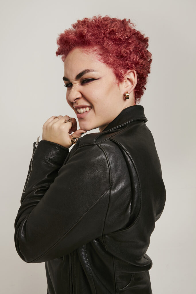 woman side on looking into the camera with pink short textured hair