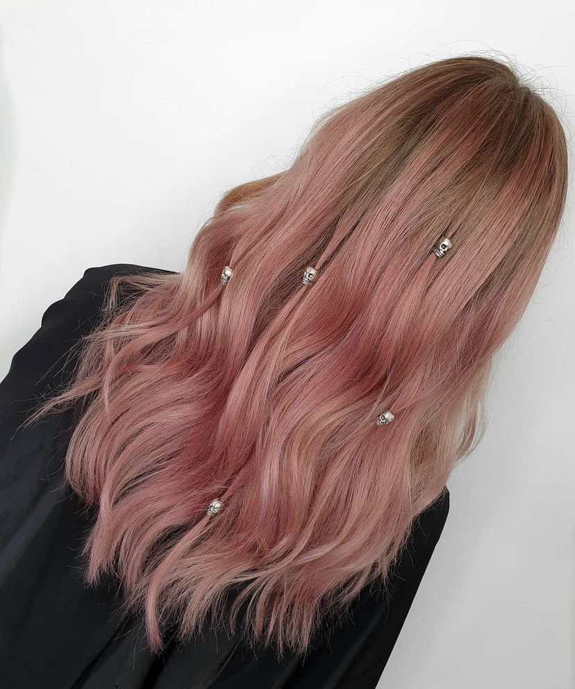 back view of a womans light pink long hair with skull clips in it