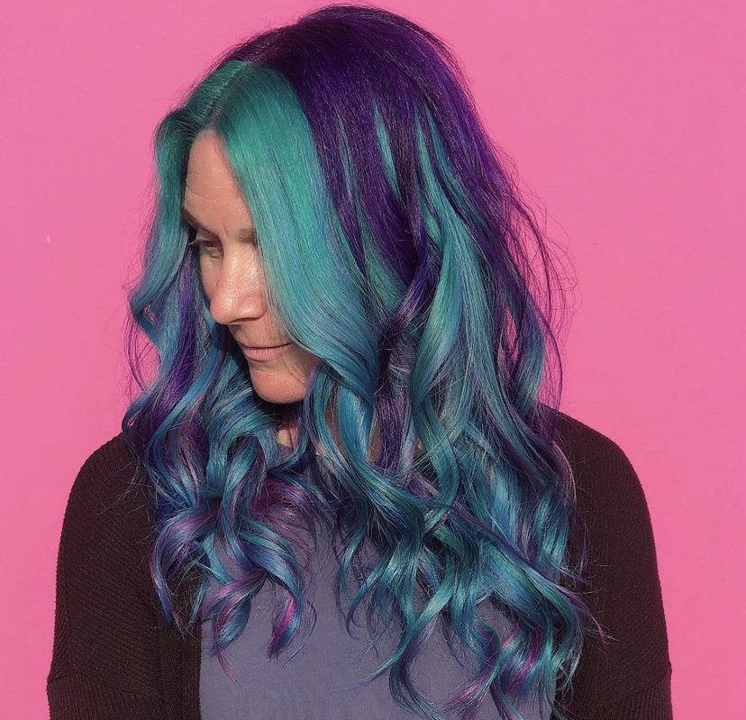 woman looking to the side with blue and purple long curled hair