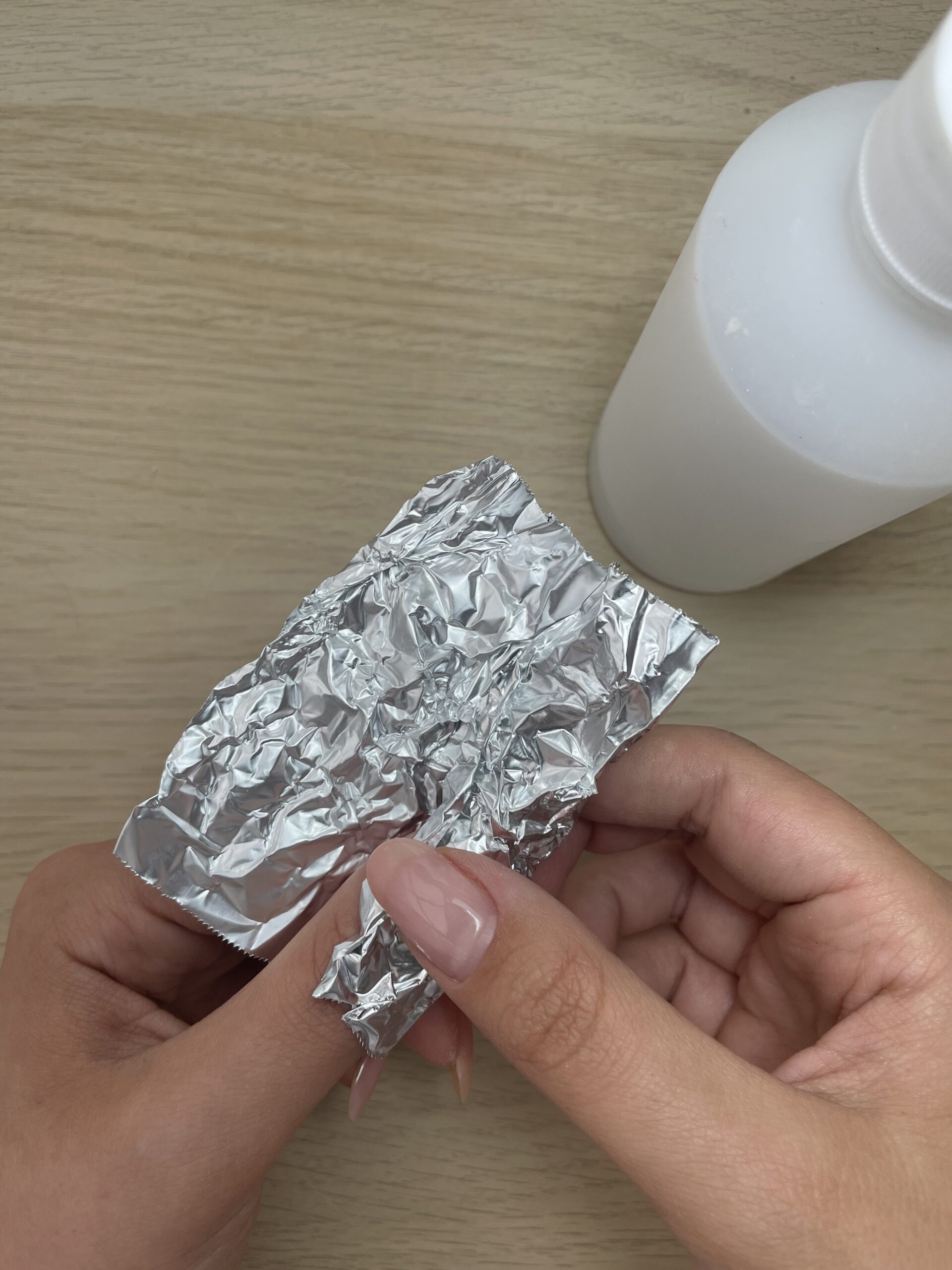 woman wipes her thumbnail with acetone and a foil wrap