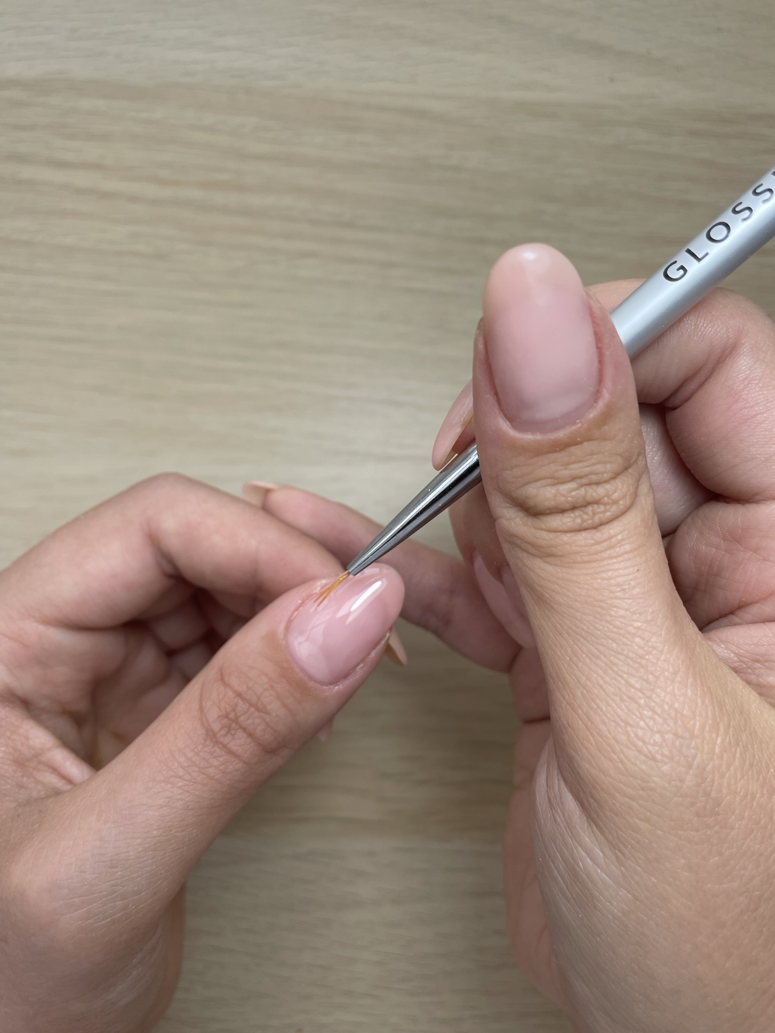 woman uses nail tool to create an apex on thumb nail