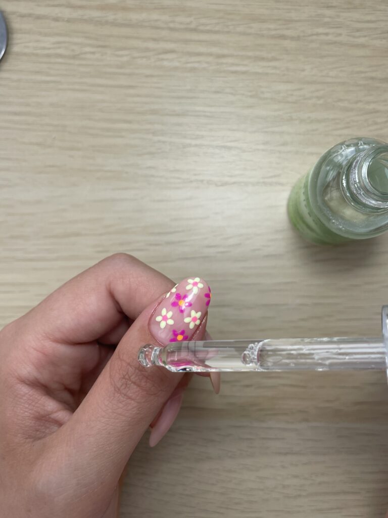 woman applies cuticle nail oil to her thumb