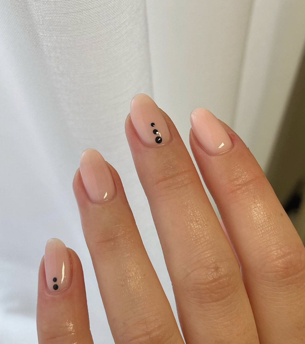 Image of a hand with pink nails and black dots
