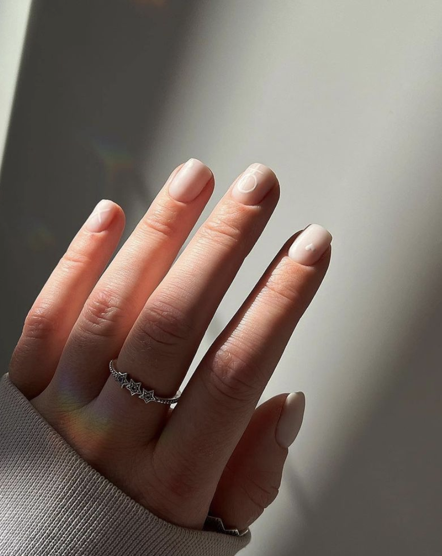 Image of a hand with pink nails, the person is wearing a silver ring