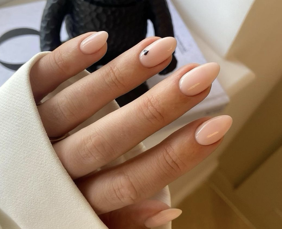 Image of almond shaped nails, one nail has a tiny black heart on it