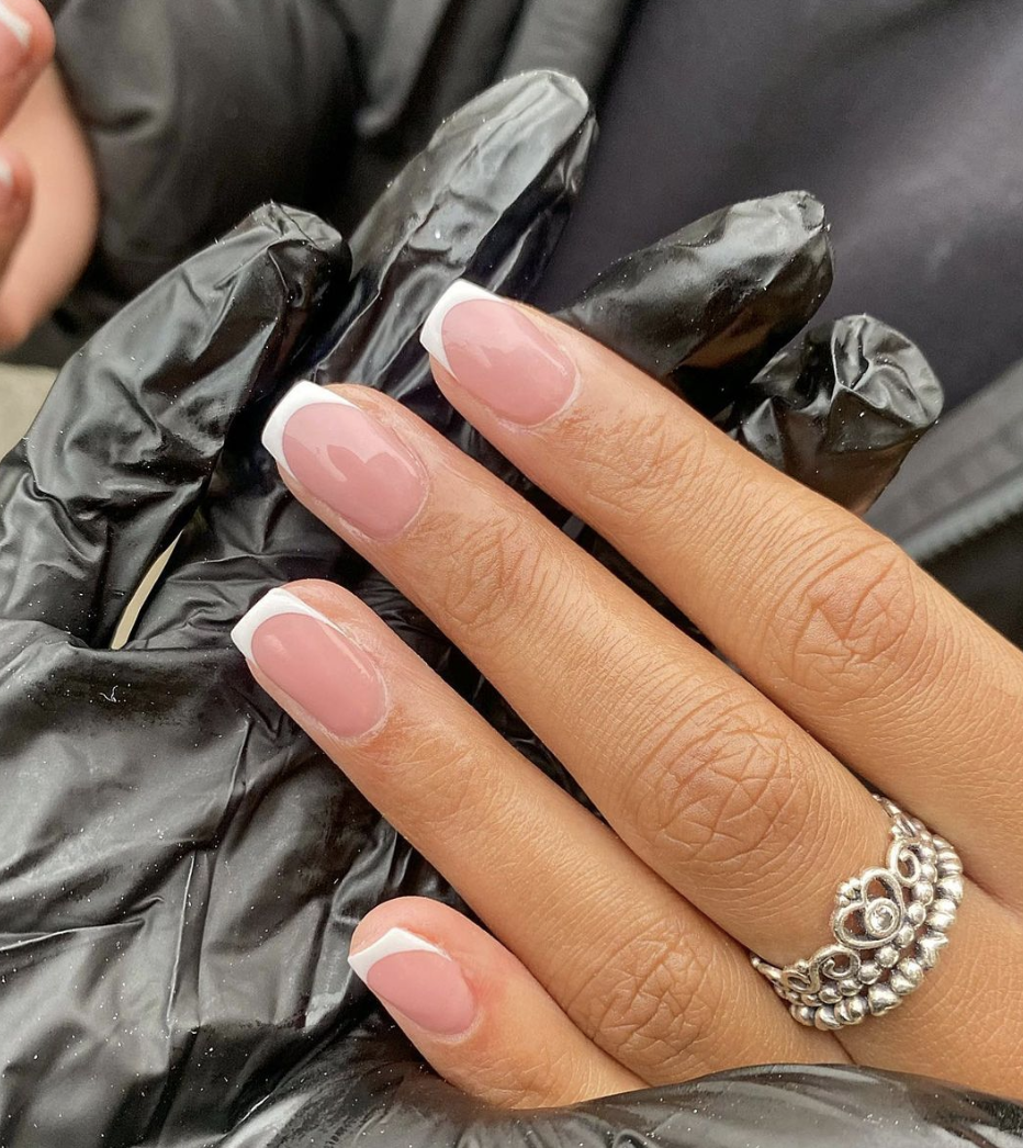 Image of pink and white nails with one finger which has a silver ring on it